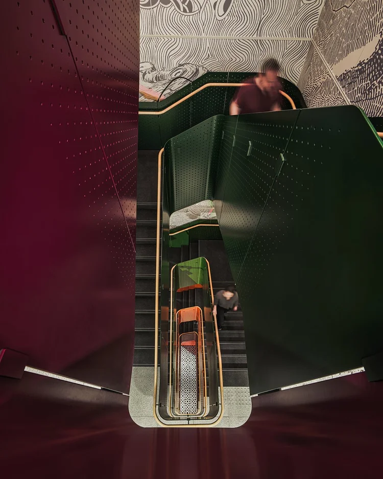 Sculptural stairwell with green and burgundy perforated panels