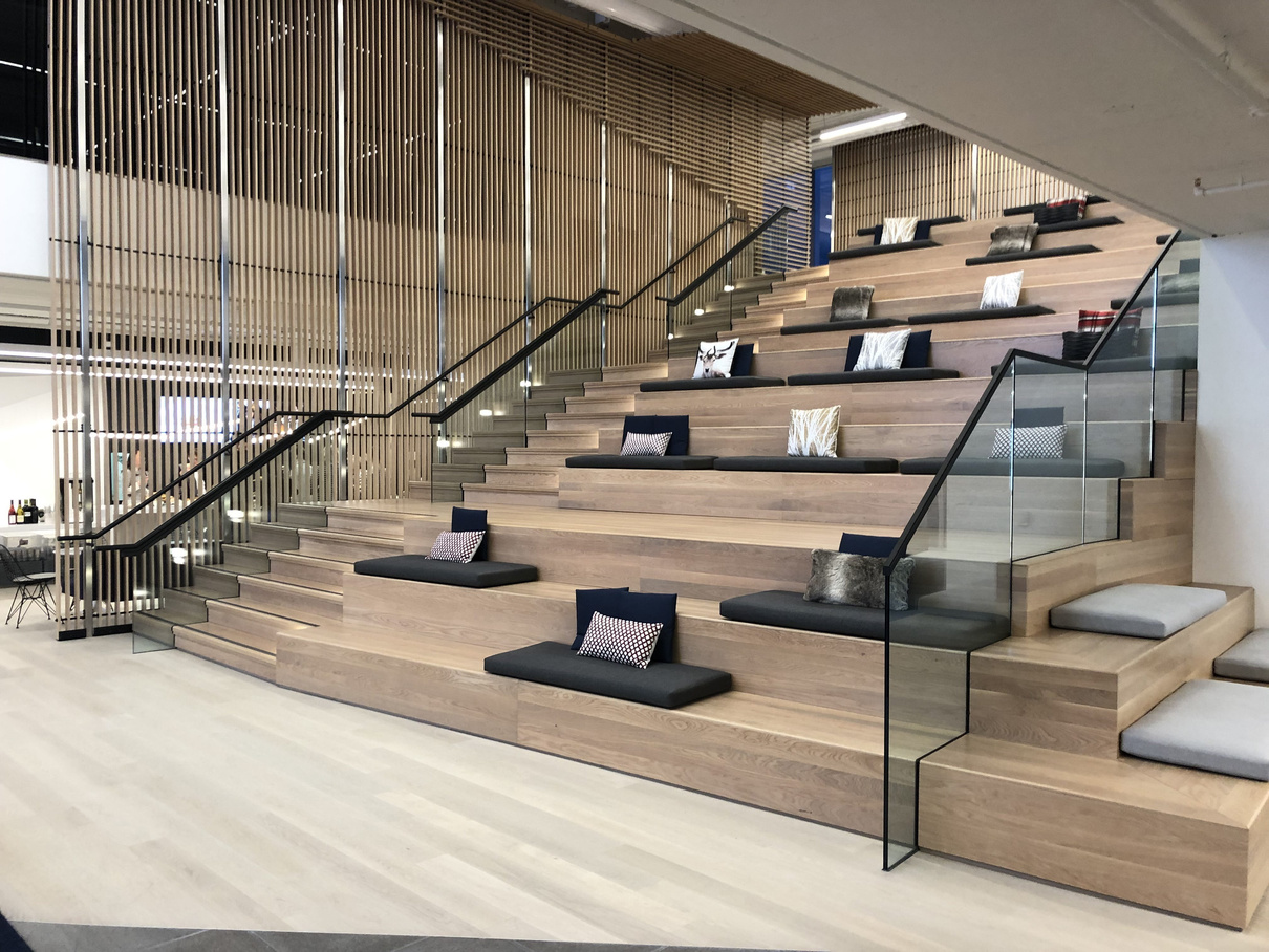 Office staircase with red handrail and lounge seating below